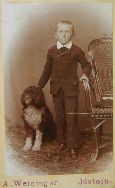 Foto realizada a un niño de familia adinerada, titulada (Spanish Poodle) perro de lana español
                        fotografía realizada por A. Weininger a finales del siglo XIX